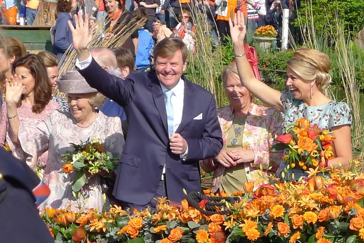 Koning Willem-Alexander zwaait, met koningin Máxima en prinses Beatrix, in De Rijp
